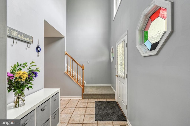 foyer entrance featuring a high ceiling, light tile patterned floors, and plenty of natural light