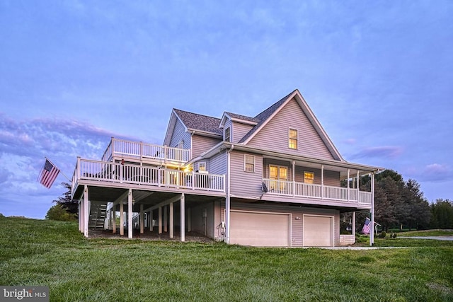 back house at dusk featuring a lawn, a garage, and a deck