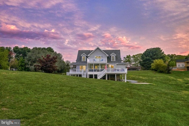 back house at dusk with a lawn and a wooden deck