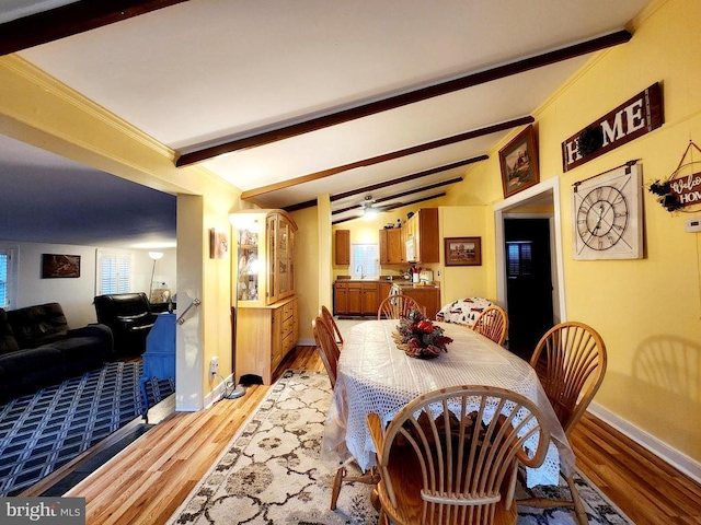 dining space featuring crown molding, light hardwood / wood-style flooring, and lofted ceiling with beams