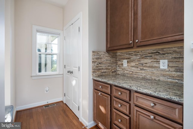 kitchen featuring backsplash, light stone countertops, and dark wood-type flooring