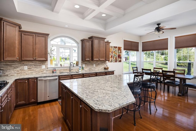 kitchen with decorative backsplash, stainless steel dishwasher, a healthy amount of sunlight, a center island, and dark hardwood / wood-style floors