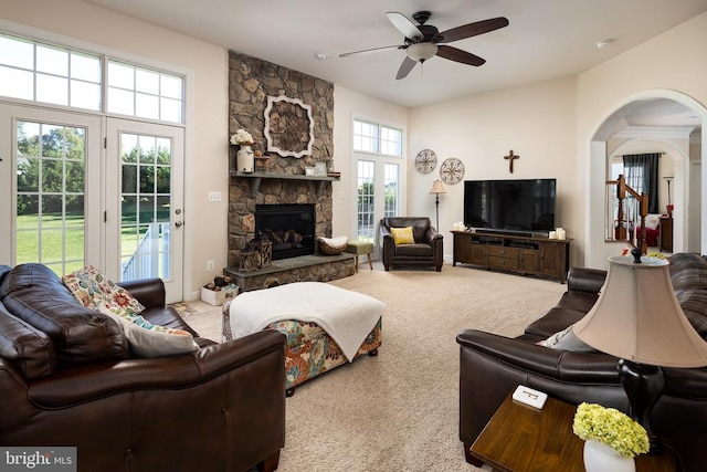 living room with ceiling fan, a stone fireplace, and carpet floors