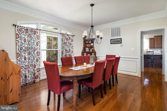 dining space with crown molding, dark hardwood / wood-style floors, and an inviting chandelier