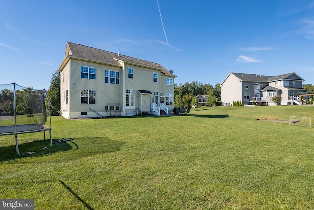 back of property with a lawn and a trampoline