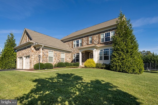 colonial inspired home featuring a garage, a front yard, and a trampoline