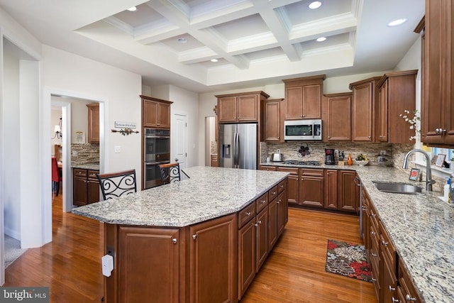 kitchen featuring decorative backsplash, stainless steel appliances, hardwood / wood-style flooring, beamed ceiling, and a center island