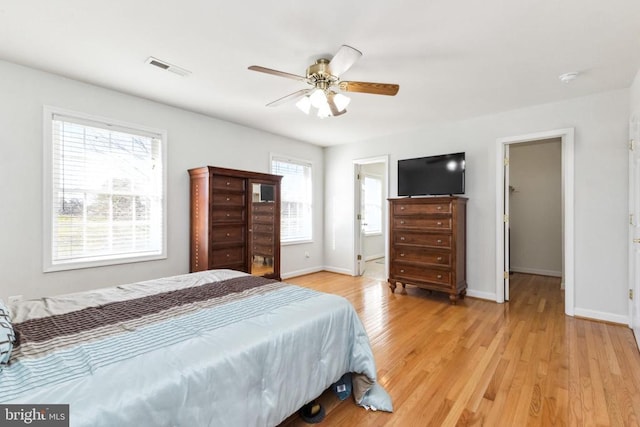 bedroom featuring a walk in closet, ceiling fan, light hardwood / wood-style floors, ensuite bath, and a closet