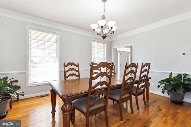 dining area featuring ornamental molding, wood-type flooring, and a notable chandelier