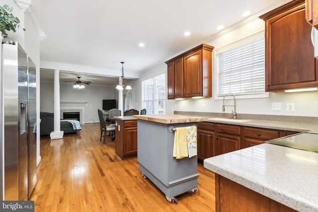 kitchen featuring wood counters, sink, hanging light fixtures, a center island, and stainless steel refrigerator with ice dispenser