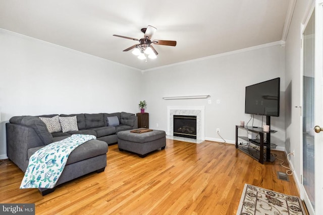 living room with ornamental molding, hardwood / wood-style floors, ceiling fan, and a high end fireplace