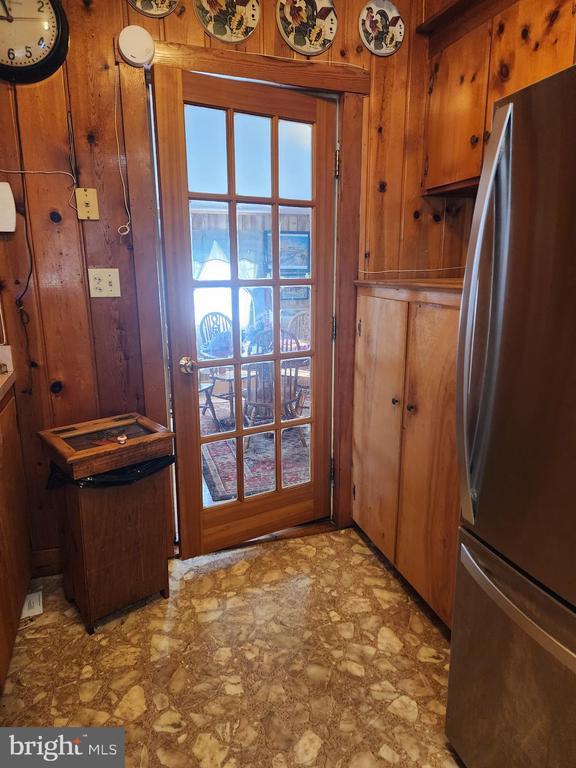 doorway to outside with wood walls