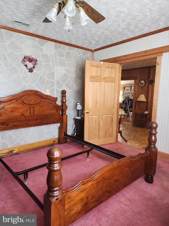 bedroom with a textured ceiling, carpet floors, ceiling fan, and ornamental molding