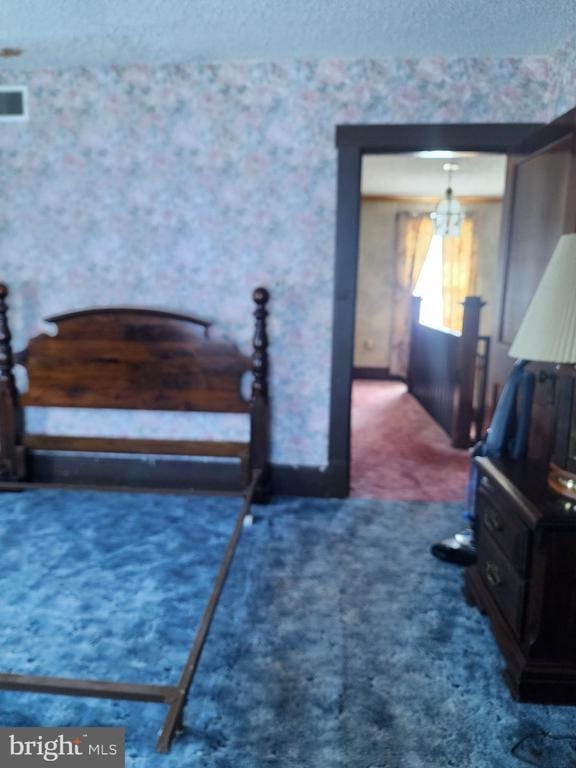 bedroom with dark carpet, a textured ceiling, and a notable chandelier