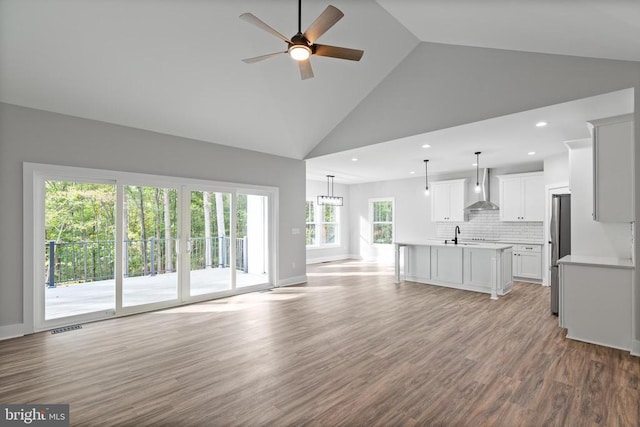 unfurnished living room with light wood-type flooring, high vaulted ceiling, ceiling fan, and sink