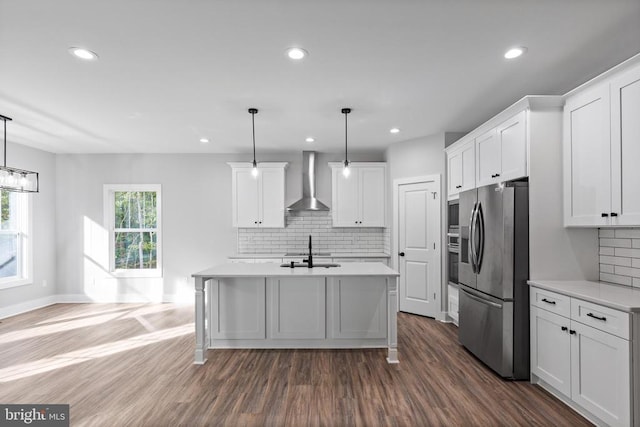 kitchen with white cabinetry, decorative light fixtures, wall chimney range hood, and appliances with stainless steel finishes