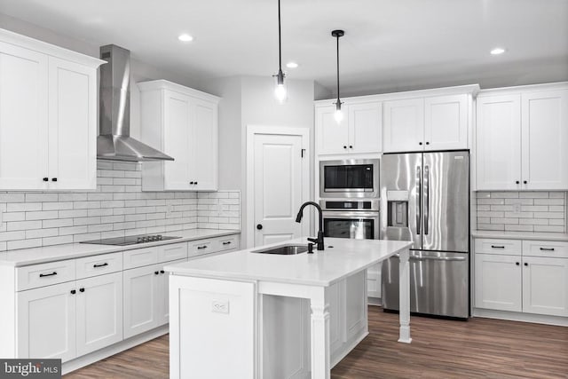 kitchen featuring hanging light fixtures, sink, wall chimney exhaust hood, appliances with stainless steel finishes, and white cabinetry