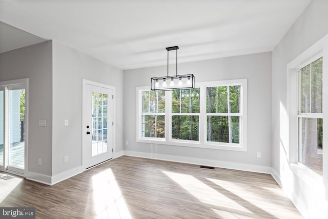 unfurnished dining area with hardwood / wood-style floors and an inviting chandelier