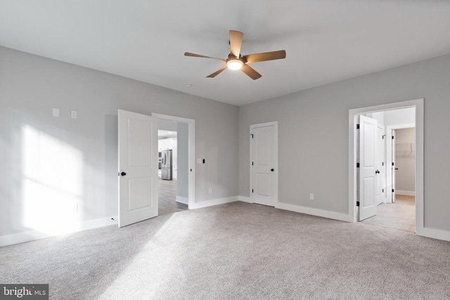 unfurnished bedroom featuring ceiling fan, stainless steel fridge, and light colored carpet