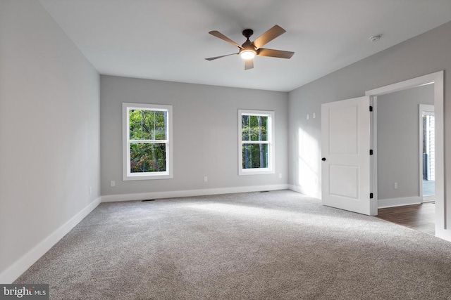 empty room featuring ceiling fan and dark carpet