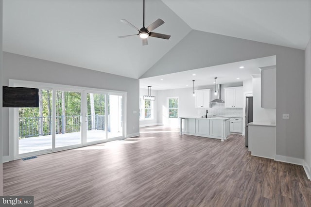 unfurnished living room with ceiling fan, sink, high vaulted ceiling, and light hardwood / wood-style flooring