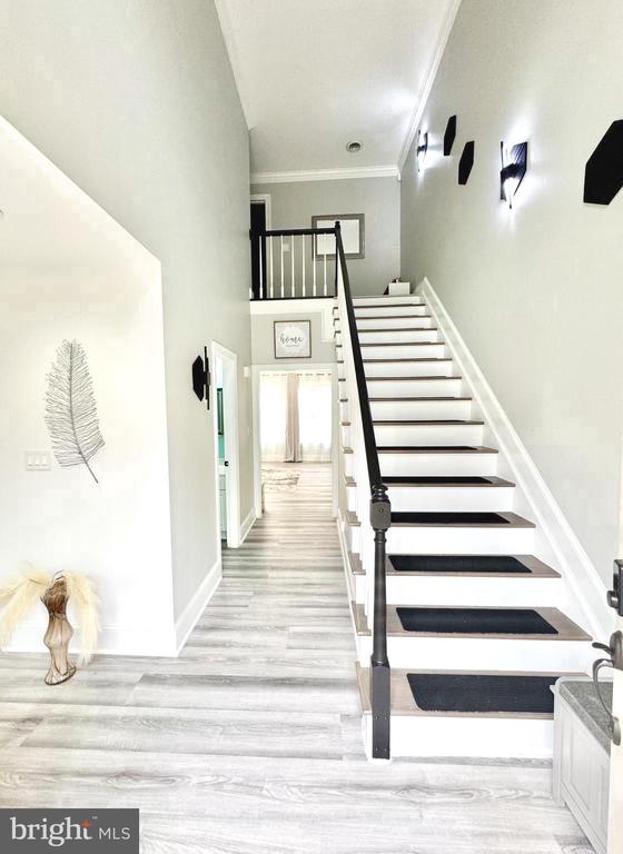 staircase with wood-type flooring and ornamental molding