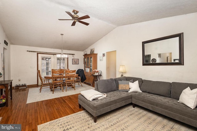 living room featuring hardwood / wood-style flooring, ceiling fan with notable chandelier, and lofted ceiling