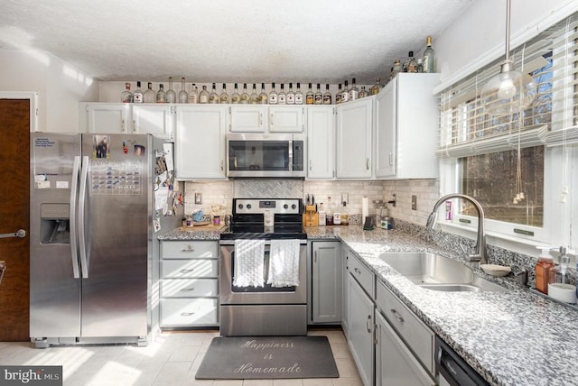 kitchen featuring sink, a textured ceiling, appliances with stainless steel finishes, tasteful backsplash, and light tile patterned flooring