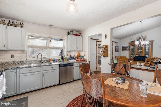 kitchen featuring sink, stainless steel dishwasher, backsplash, pendant lighting, and lofted ceiling