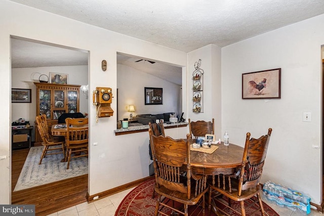 dining area with a textured ceiling, light hardwood / wood-style floors, and lofted ceiling