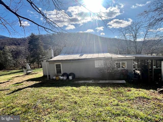 view of side of home featuring a lawn, a sunroom, and a mountain view