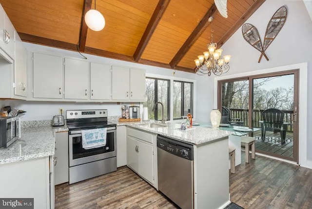 kitchen with sink, white cabinets, stainless steel appliances, and decorative light fixtures