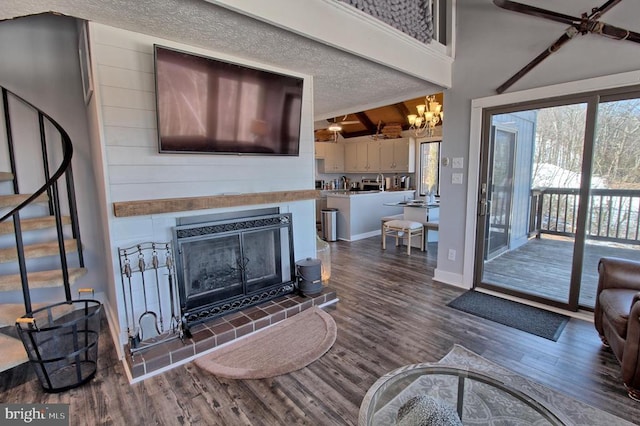 living room featuring a high ceiling, dark hardwood / wood-style floors, a textured ceiling, beamed ceiling, and a tiled fireplace