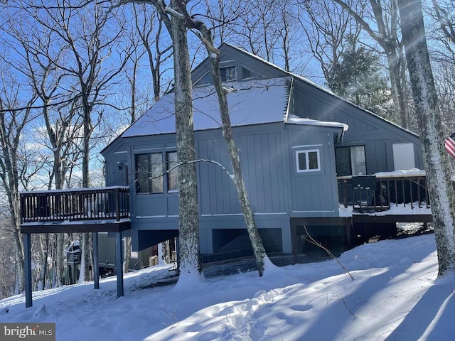 snow covered house featuring a wooden deck