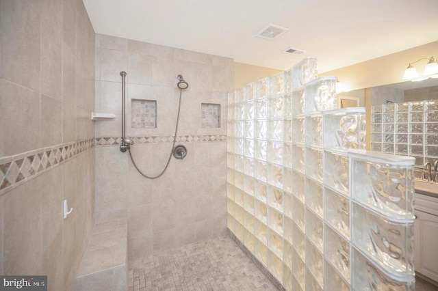 bathroom with a tile shower and vanity