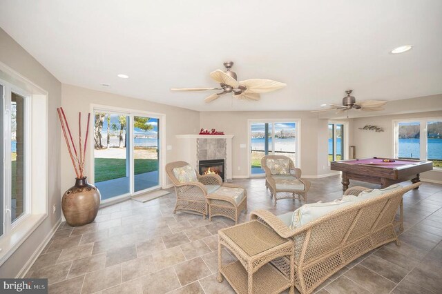 playroom with ceiling fan, a water view, a fireplace, and pool table