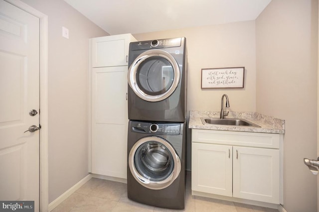 laundry area featuring cabinets, light tile patterned flooring, stacked washer / dryer, and sink