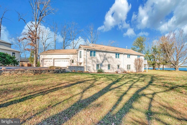 rear view of house featuring a lawn, a water view, and a garage