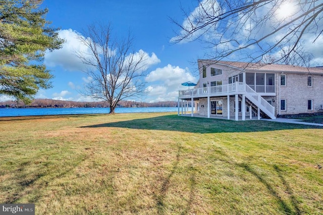 view of yard with a patio, a water view, and a sunroom