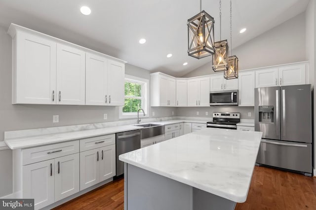 kitchen featuring white cabinets, a center island, appliances with stainless steel finishes, and vaulted ceiling