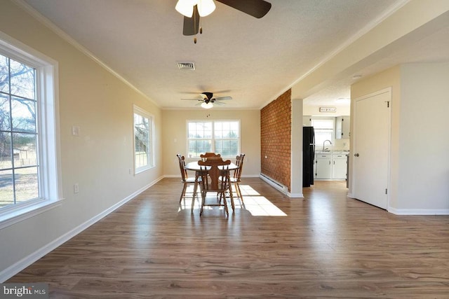 dining room with ceiling fan, sink, brick wall, crown molding, and hardwood / wood-style floors