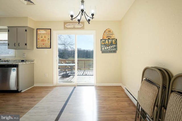 unfurnished dining area featuring hardwood / wood-style floors, a baseboard radiator, and a chandelier