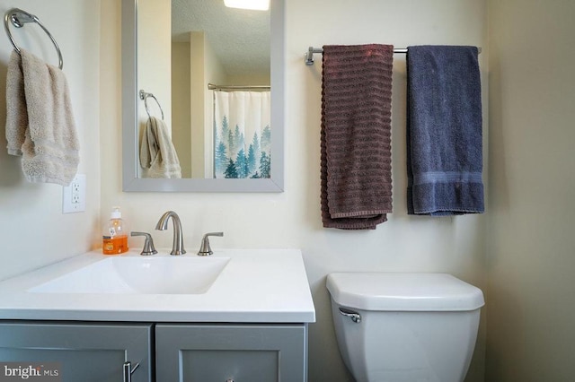 bathroom featuring vanity, a textured ceiling, and toilet