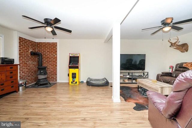 living room with a wood stove, ceiling fan, and light hardwood / wood-style floors