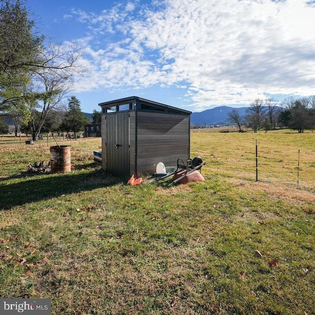 view of outdoor structure featuring a mountain view, a yard, and a rural view