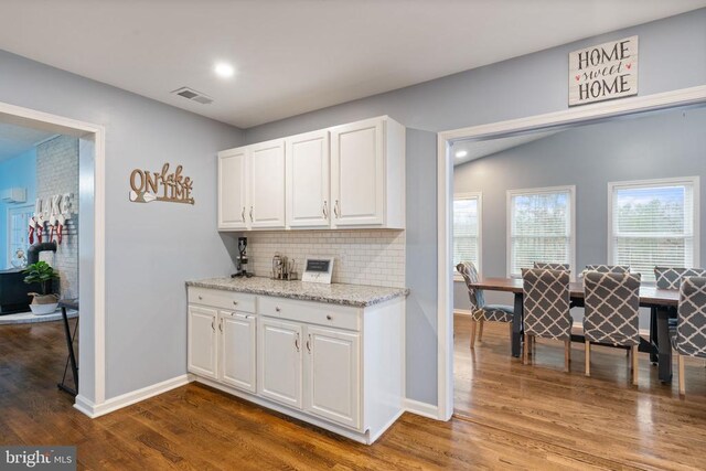 kitchen featuring backsplash, white cabinetry, light stone countertops, and hardwood / wood-style flooring