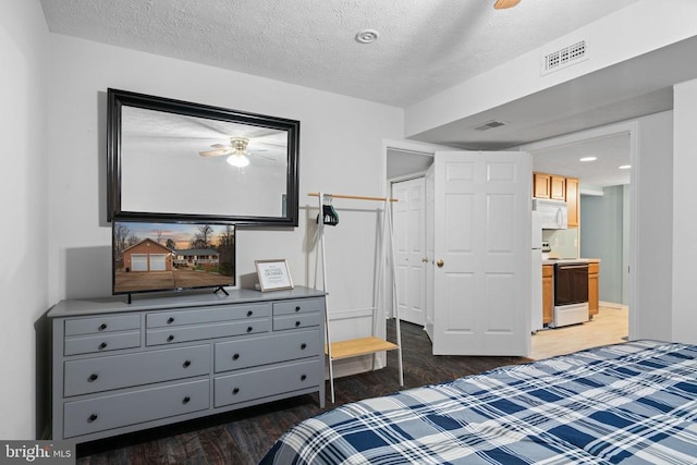 bedroom with ensuite bath, dark wood-type flooring, and a textured ceiling