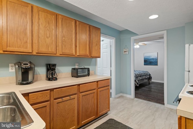 kitchen with sink, white fridge, a textured ceiling, and light wood-type flooring