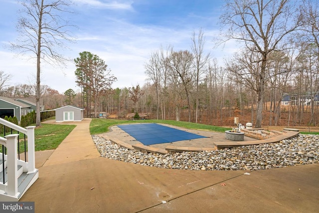 view of pool featuring an outbuilding, a patio, and an outdoor fire pit