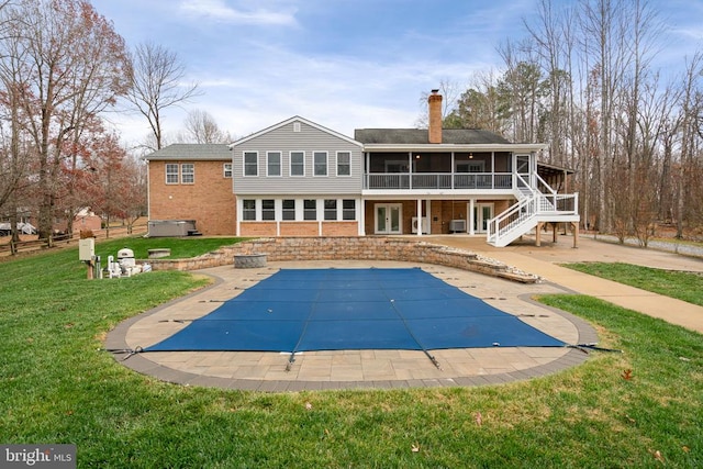 back of house with a yard, a patio, a covered pool, and a sunroom